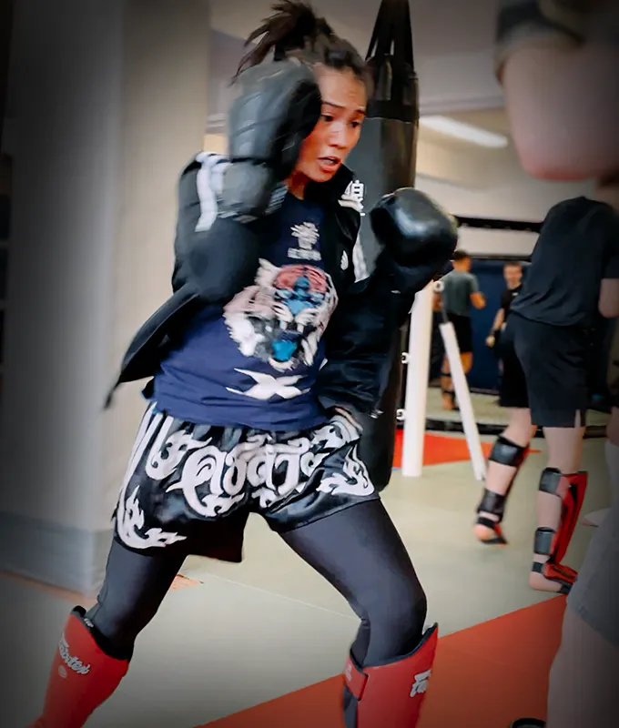 Eine junge Frau in Bewegung bei einer Partnerübung im Kickboxtraining im Combat Club Cologne