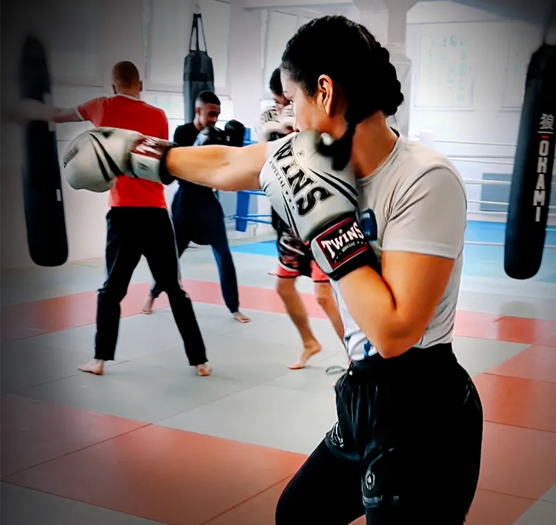 Junge Frau macht Schattenboxen in Boxhandschuhen beim Boxtraining in Köln im Combat Club Cologne Gym
