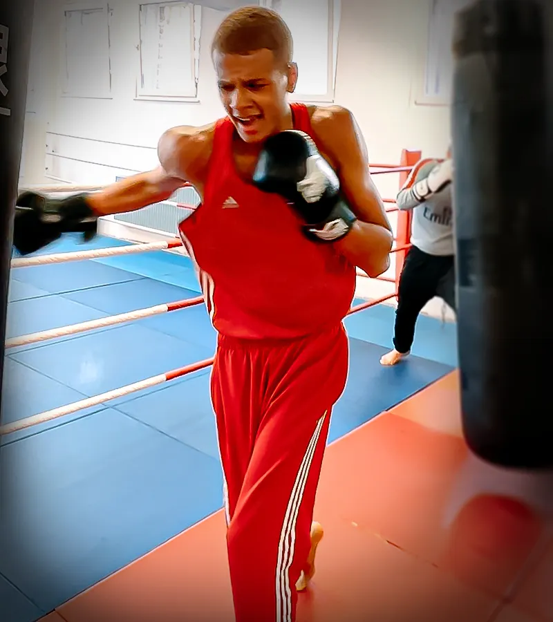 Ein Teenager powert sich aus am Sandsack im Boxunterricht in Köln
