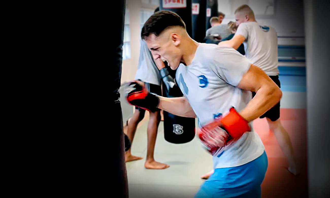Junger Kämpfer in Boxhandschuhen am Sandsack beim Boxen in Köln im Combat Club Cologne Gym