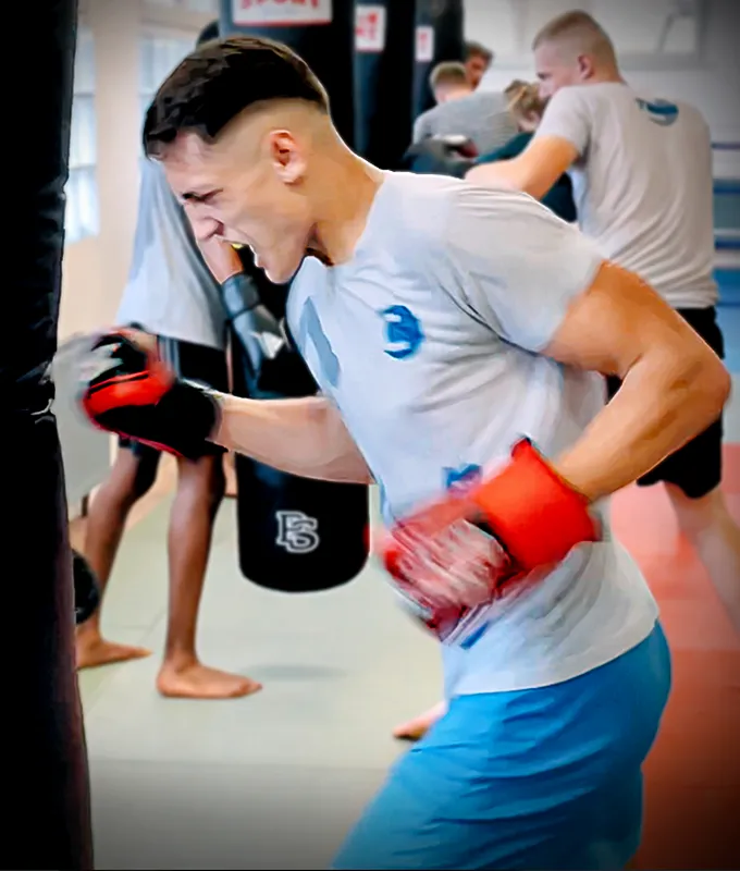 Junger Kämpfer in Boxhandschuhen am Sandsack beim Boxen in Köln im Combat Club Cologne Gym