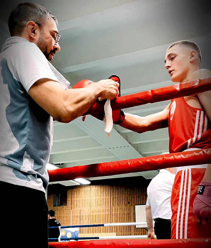 Combat Club Head Coach Mike Cüppers zieht seinem Schüler im Boxring den Handschuh aus nach einem Amateur Wettkampf