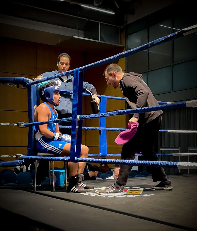 Boxen Köln: Boxtrainer redet mit seinem Boxer in der Boxringecke während der Pause bei einem Boxkampf