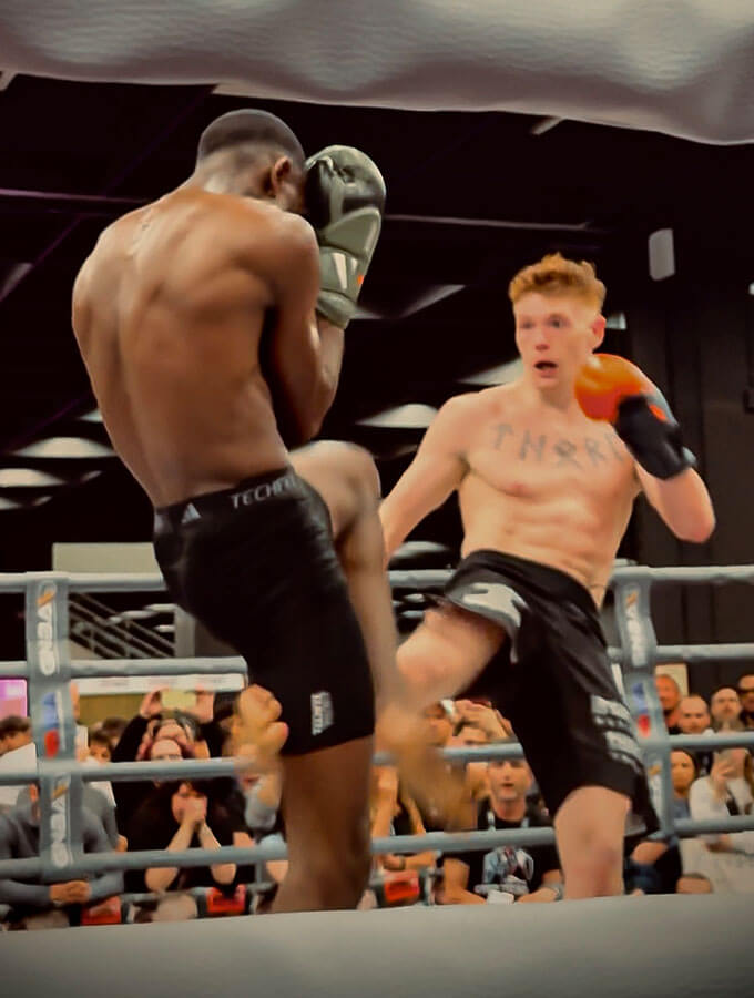 Kickboxen Köln: Ein K1-Knockout auf der FIBO 2025 bei der GMC Olympix Veranstaltung. 2 K1-Kämpfer kämpfen im Boxring gegeneinander. Der Fighter vom Combat Club setzt gerade zu einem wirkungsvollen K1 Low Kick ein
