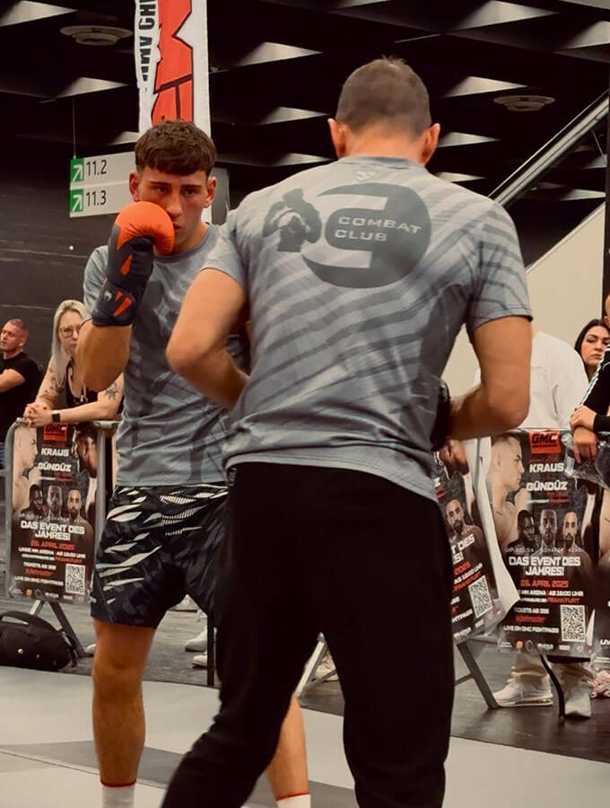 Kickboxen in Köln: K1 Fight auf der FIBO 2025 bei der GMC Olympix Veranstaltung. Der Combat Club Coach macht Pratzentraining mit seinem Schüler vor dem Wettkampf.