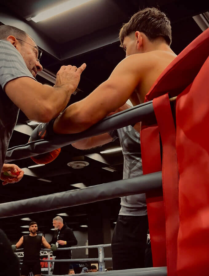 K1-Kickboxen Köln: K1 Fight auf der FIBO 2025 bei der GMC Olympix Veranstaltung. Der Combat Club Coach redet mit seinem Kämpfer in der Ringecke während der Kampfpause.