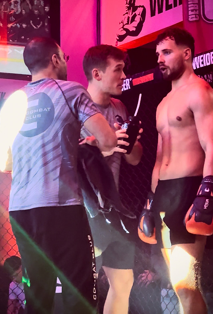 K1 GMC Olympix – zwei Coaches von Combat Club Cologne reden mit ihrem K1 Fighter in der Kampfpause im MMA-Cage