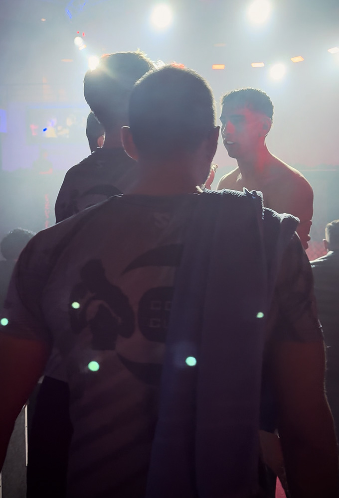 K1 GMC Olympix – zwei Coaches und der K1 Fighter von Combat Club Cologne stehen gemeinsam vor dem MMA-Cage vor dem K1 Wettkampf