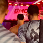 K1 GMC Olympix – zwei Coaches und der K1 Fighter von Combat Club Cologne laufen gemeinsam zum MMA-Cage vor dem K1 Wettkampf
